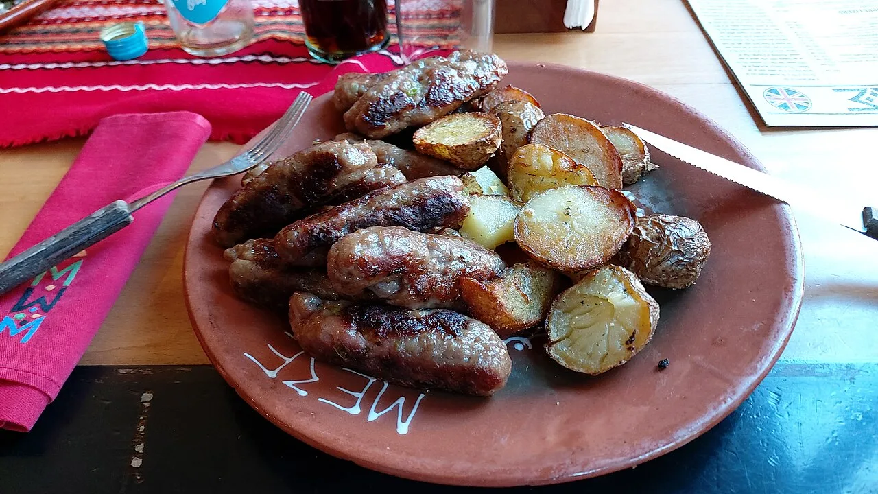 A plate of grilled ćevapi with chopped raw onion served at a Belgrade kafana