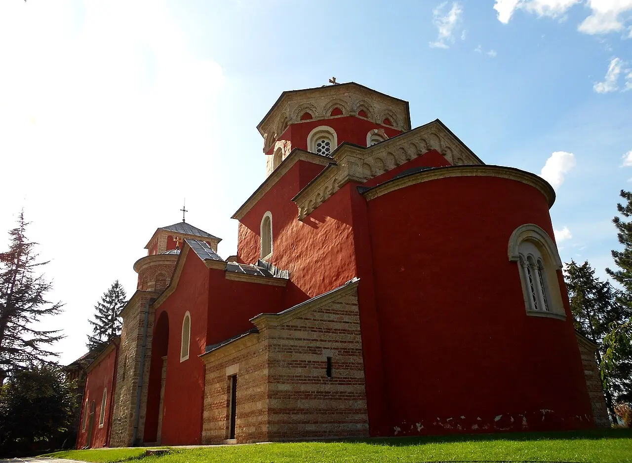 The deep red walls and domes of Zica monastery near Kraljevo under a blue sky