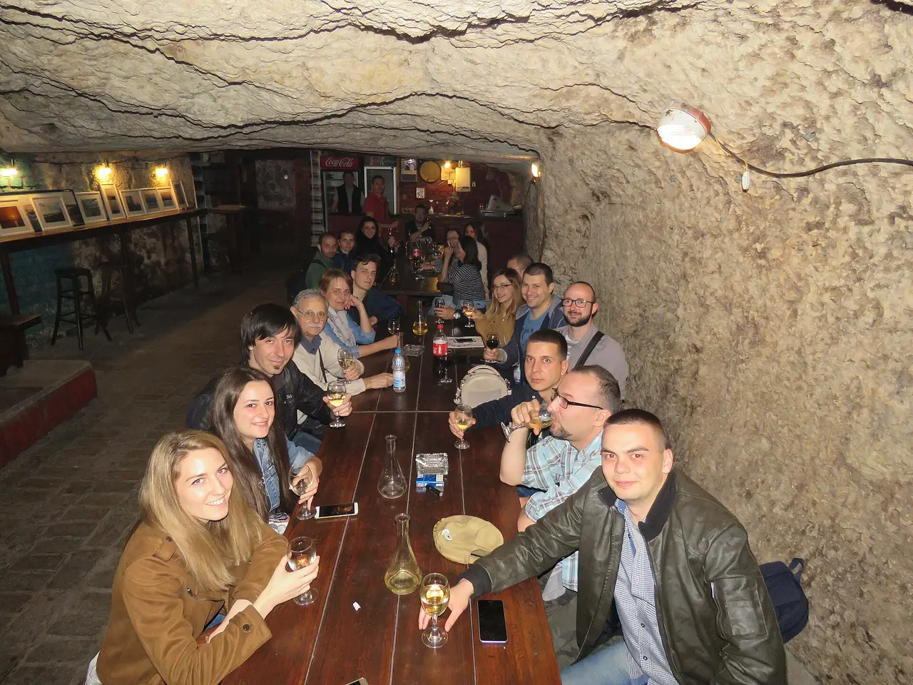 An underground wine cellar in Belgrade with stone walls, barrels and bottles on wooden racks