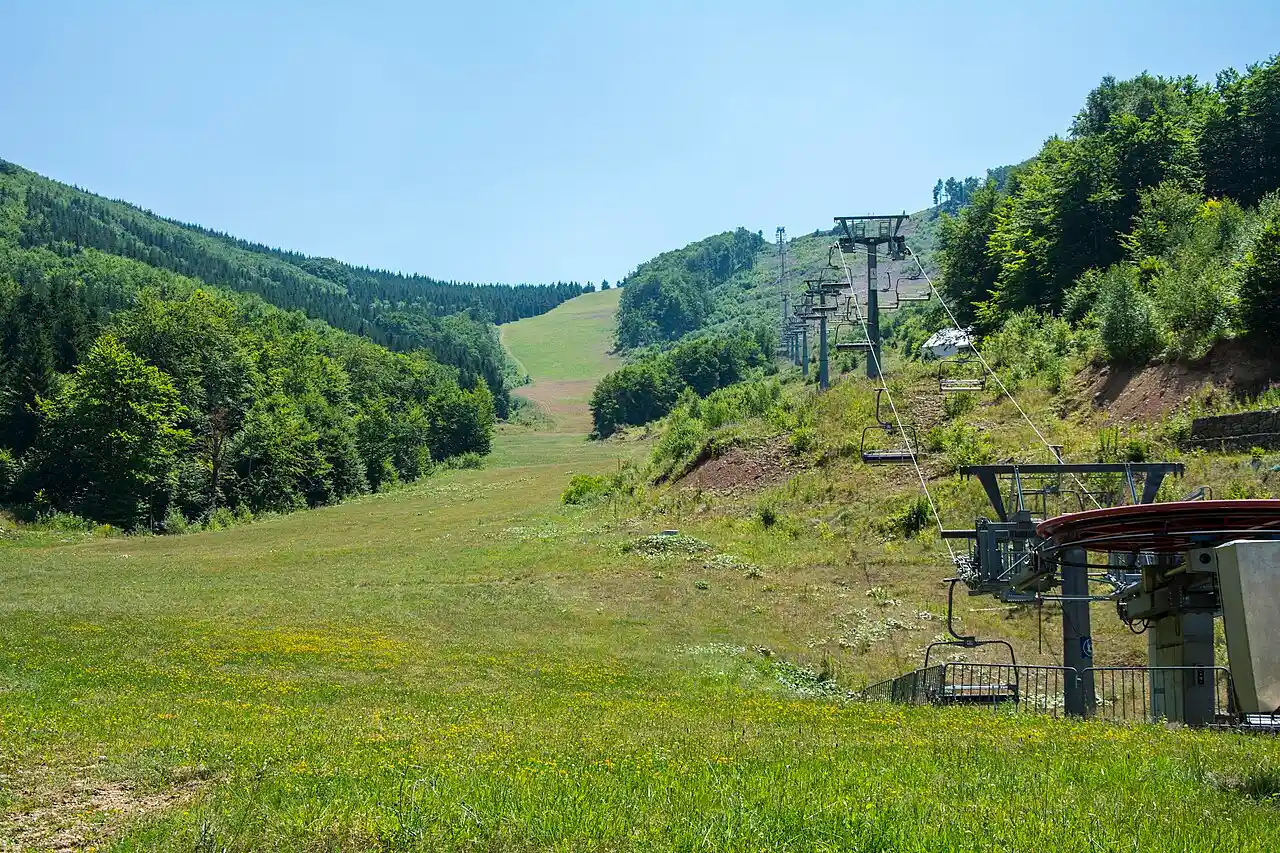 The Konjarnik piste and chairlift line at Stara Planina ski centre cutting through forest, seen in summer