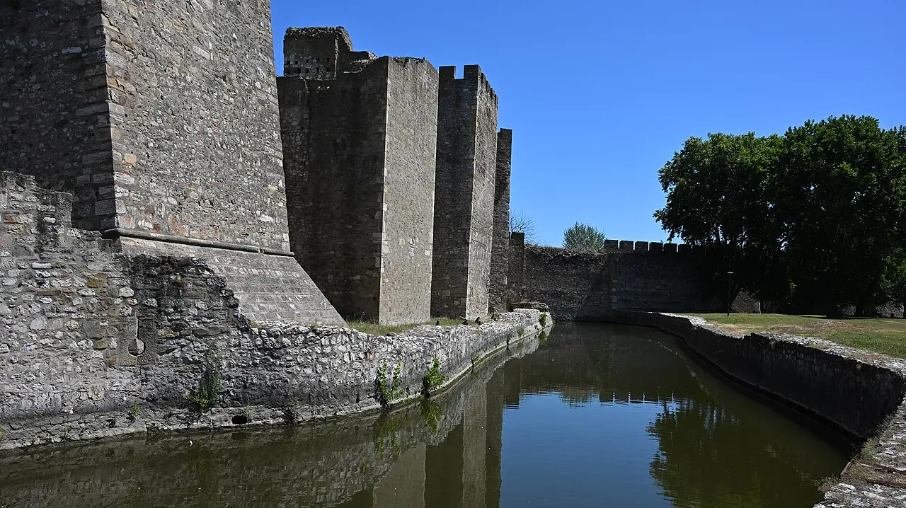 The stone ramparts and towers of Smederevo Fortress rising above the water-filled moat on the Danube bank