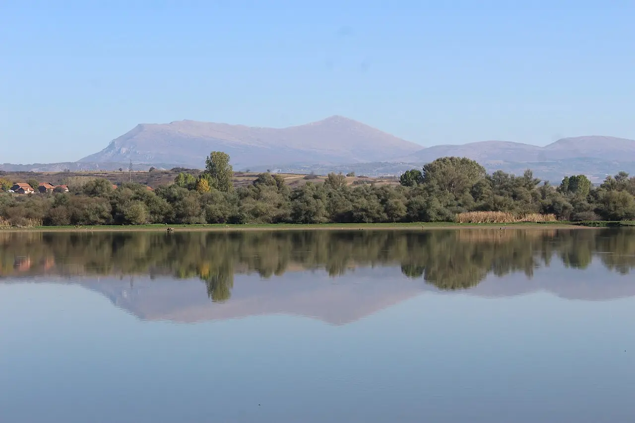 Calm water of artificial Bovan Lake west of Sokobanja with forested hills beyond