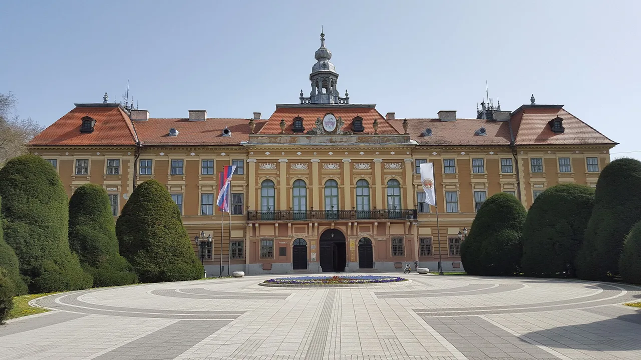 The Bačko-Bodrog County Hall (Županija) in Sombor behind park trees under a clear sky