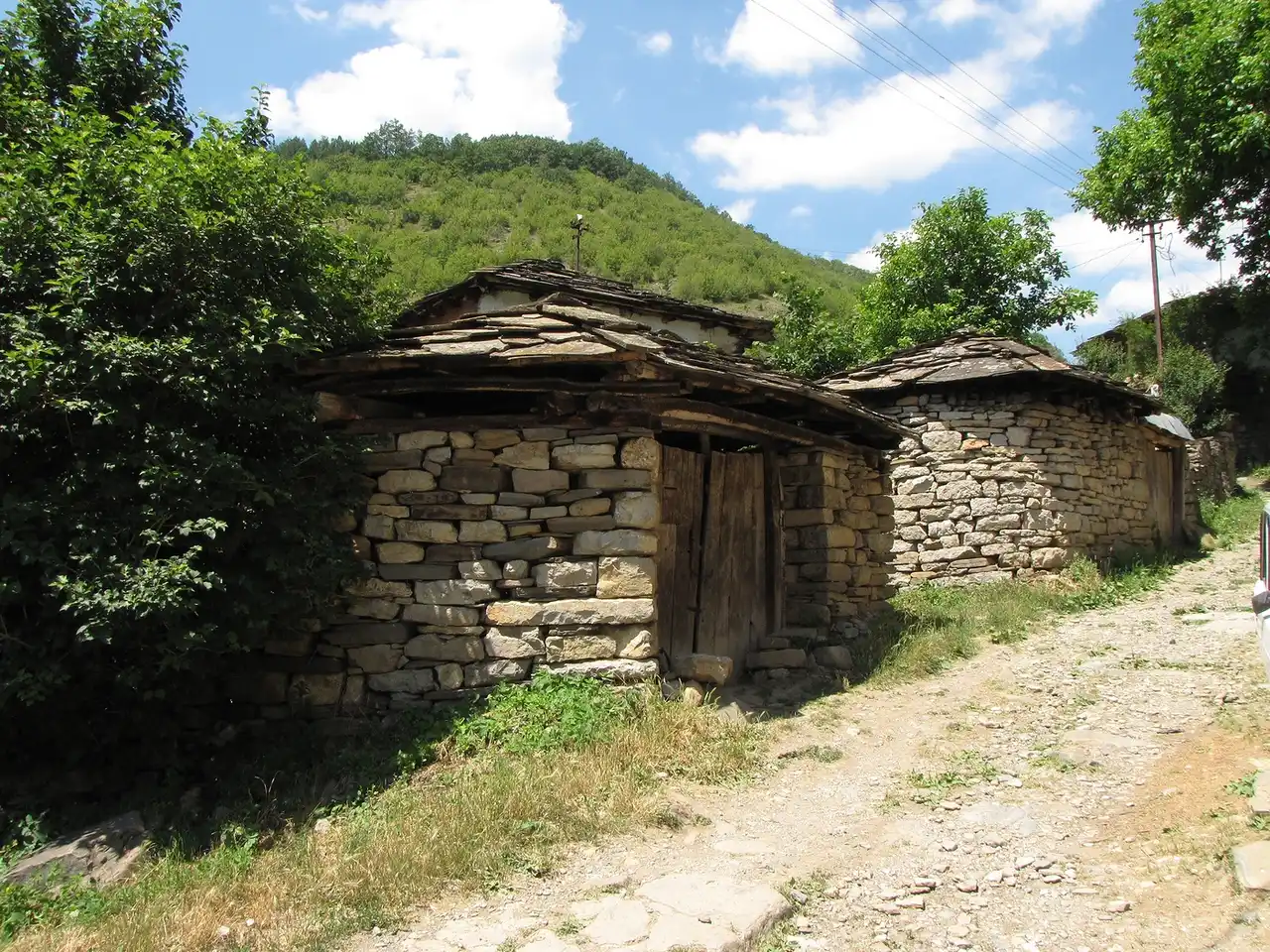 Dry-stone houses with stone-slab roofs on a rough lane in the village of Gostuša on Stara Planina