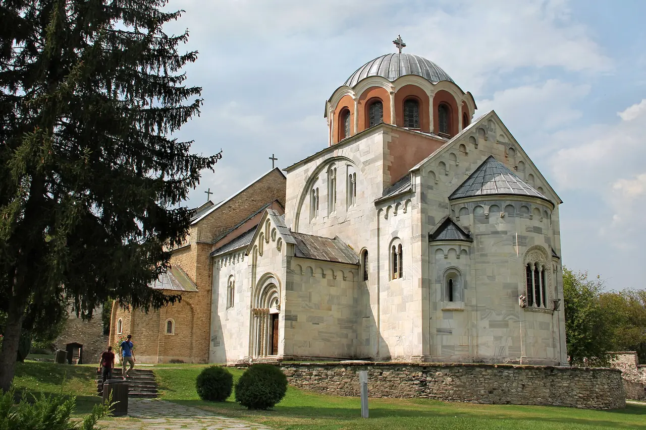 The white marble Church of the Virgin at Studenica Monastery, with its dome and Romanesque portals, seen across the monastery lawn