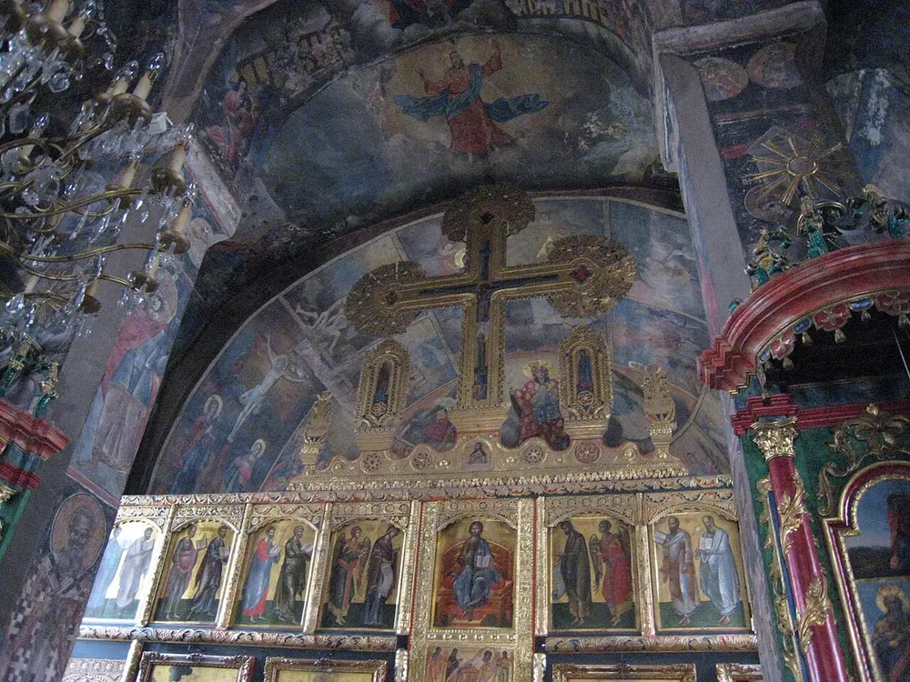 The frescoed interior and gilded iconostasis of a church at Studenica Monastery, with painted saints and a Crucifixion
