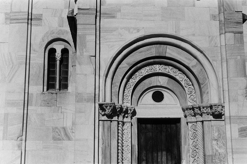 A carved white marble Romanesque portal and window on the Church of the Virgin at Studenica, with columns and sculpted capitals