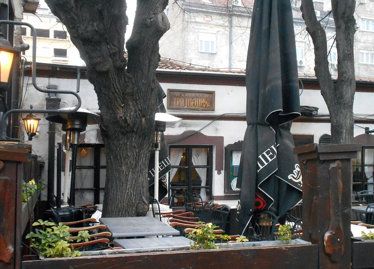 The terrace of the historic Tri Šešira kafana on Skadarlija with its old sign and heaters under a bare tree