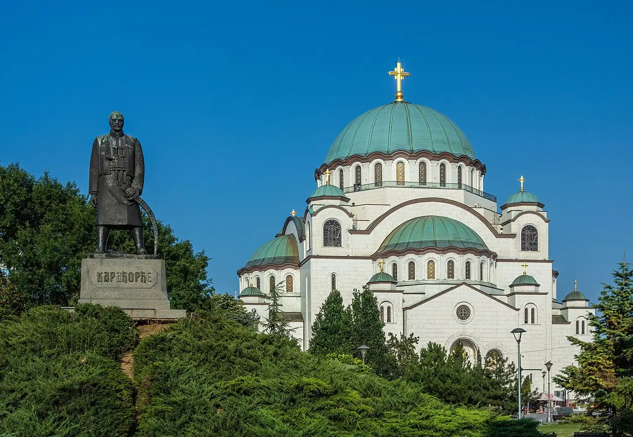 The huge white Church of Saint Sava in Belgrade with its central green dome under a blue sky