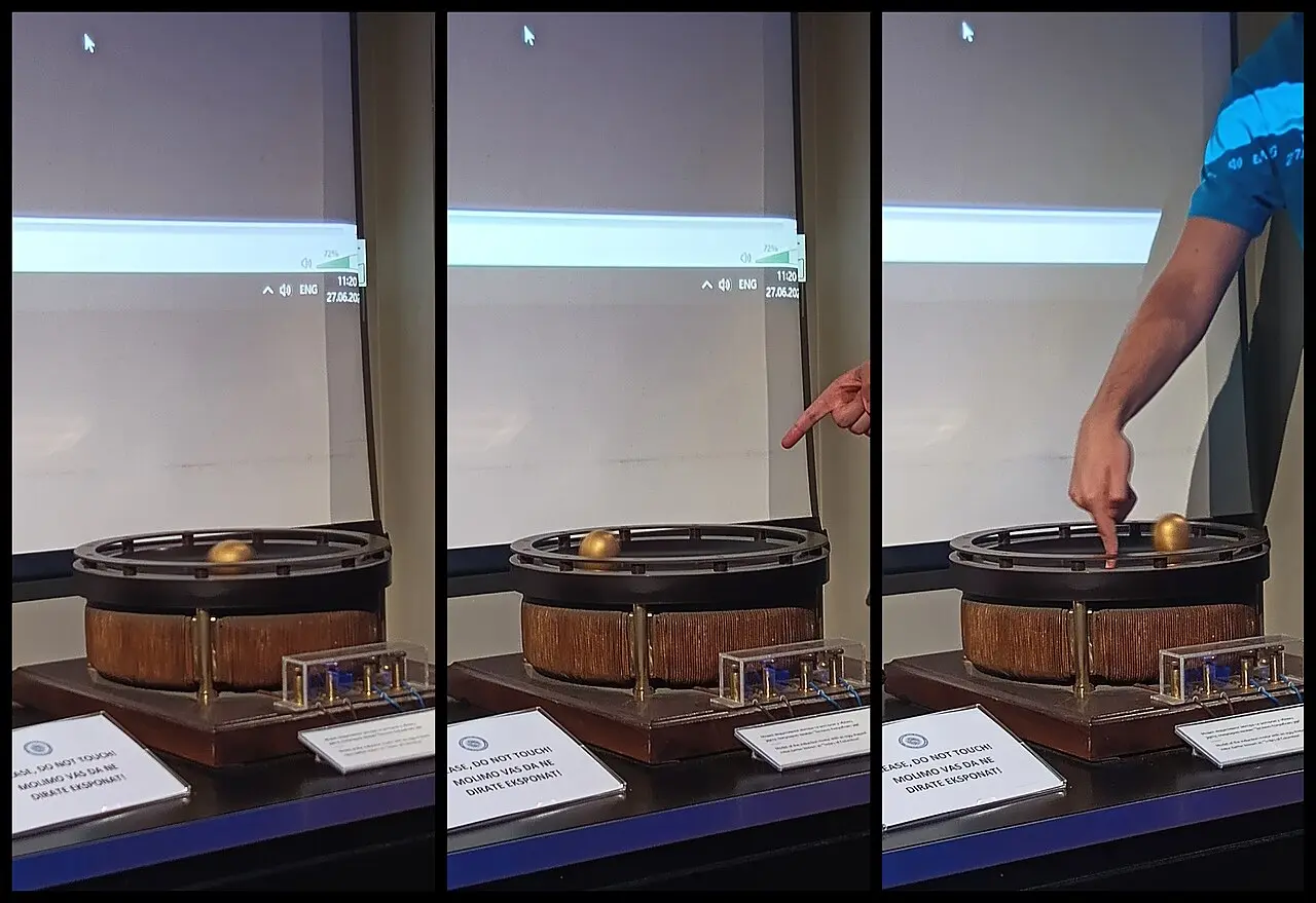 A guide demonstrating a working replica of Tesla's rotating magnetic field with a spinning golden egg at the Nikola Tesla Museum