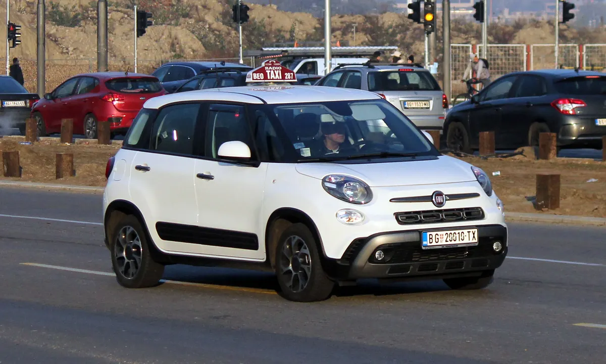 A white Belgrade taxi with a Radio Beo Taxi roof sign, driving through city traffic