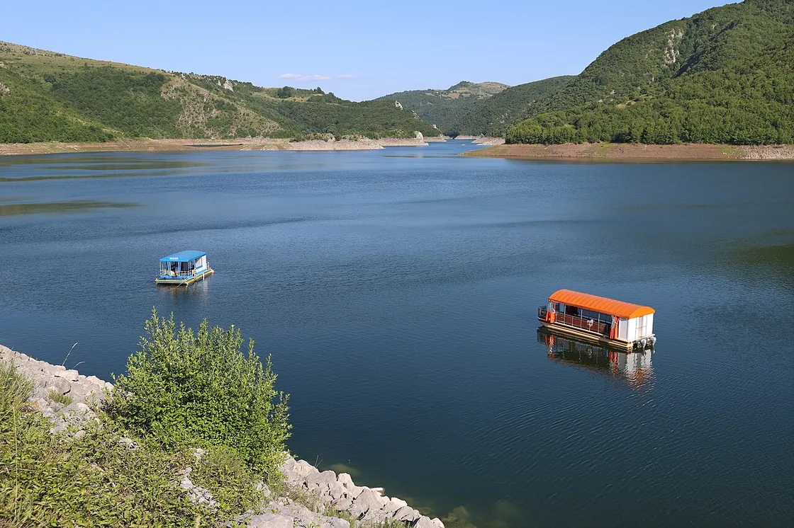 Two covered tourist pontoon boats on the calm Uvac reservoir between green canyon walls