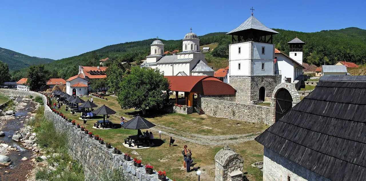 The white church, bell tower and walled courtyard of Mileseva monastery with the Milesevka stream running past