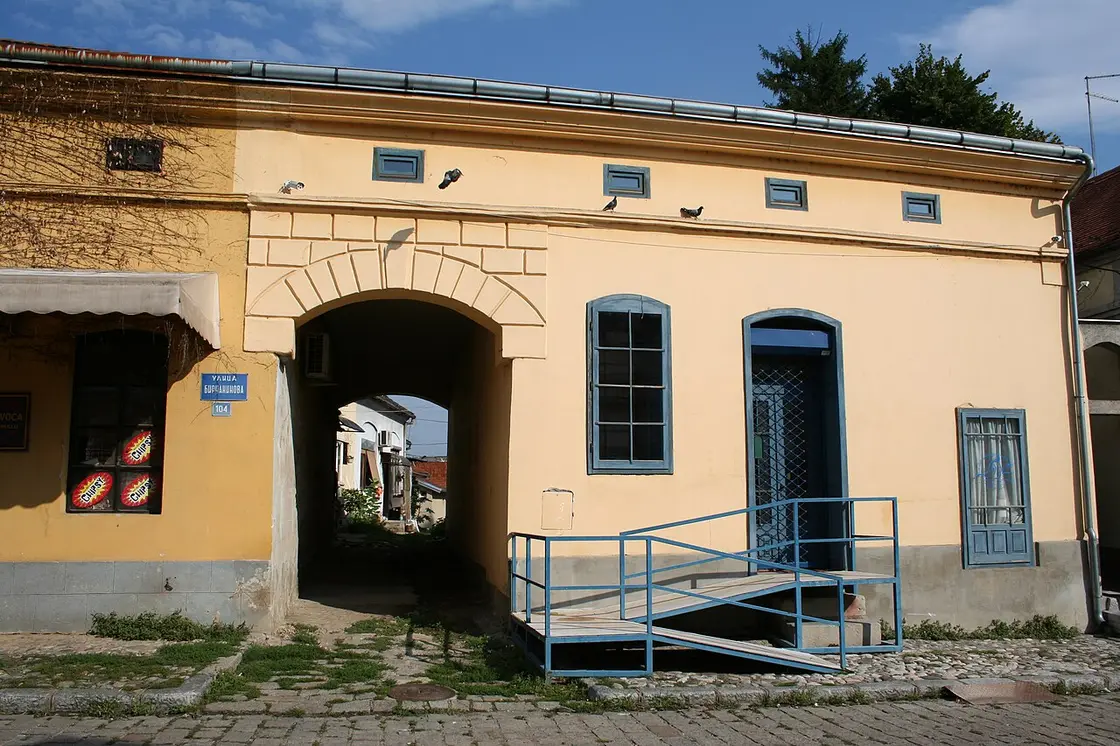 A yellow 19th-century building on Bircaninova street in Tesnjar with a stone archway leading to a courtyard
