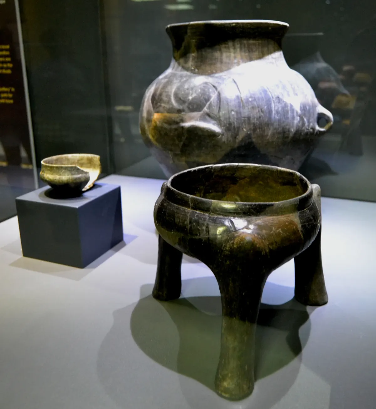 Vinca-culture pottery on display, including a dark burnished vessel with a modelled animal snout and a three-legged bowl