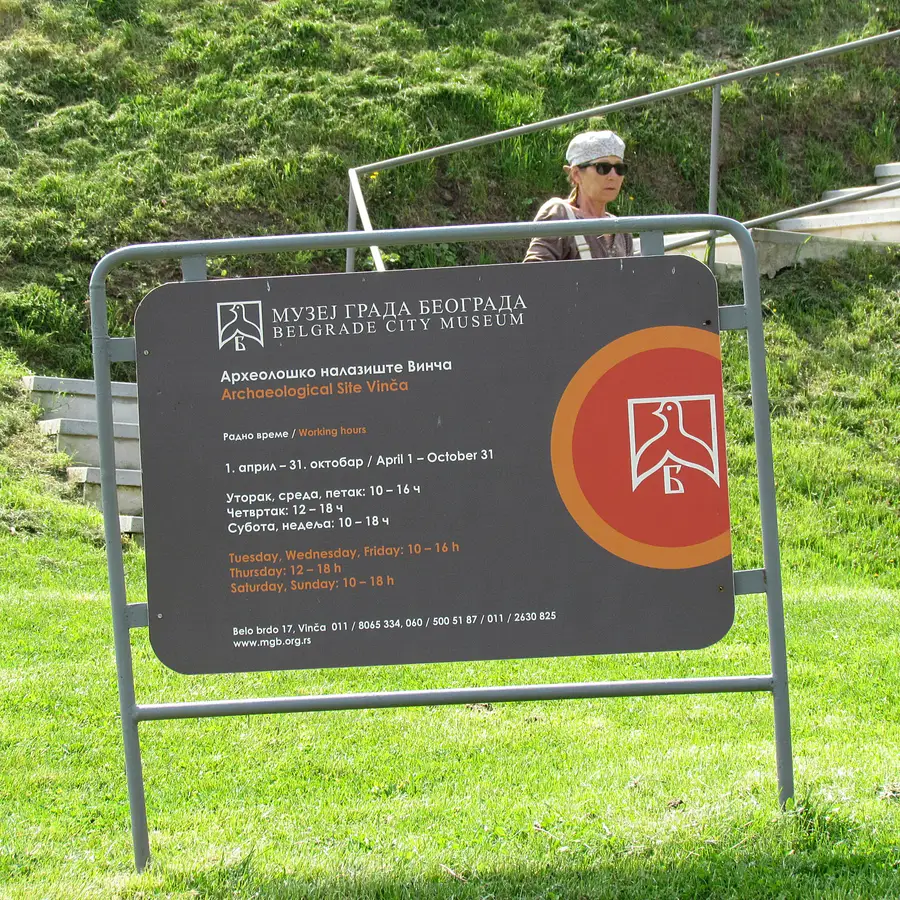 The Belgrade City Museum's posted signboard at the Vinca site, listing seasonal opening hours in Serbian and English