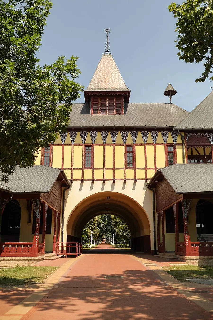 The yellow half-timbered Grand Terrace building and its tree-lined promenade at Lake Palić