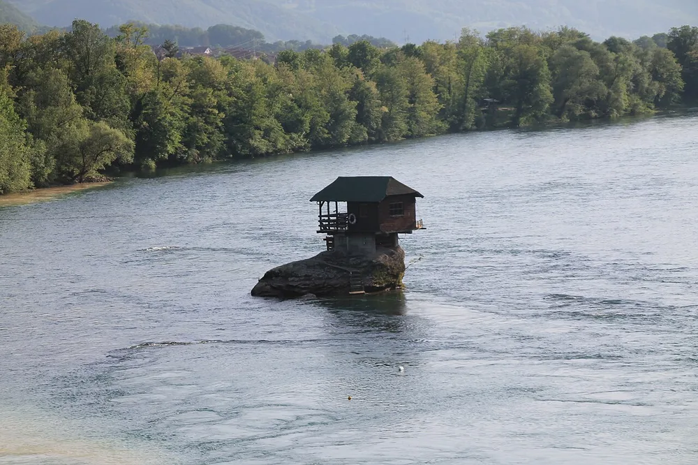 The small wooden Drina River House standing alone on a rock in the middle of the green Drina river near Bajina Basta