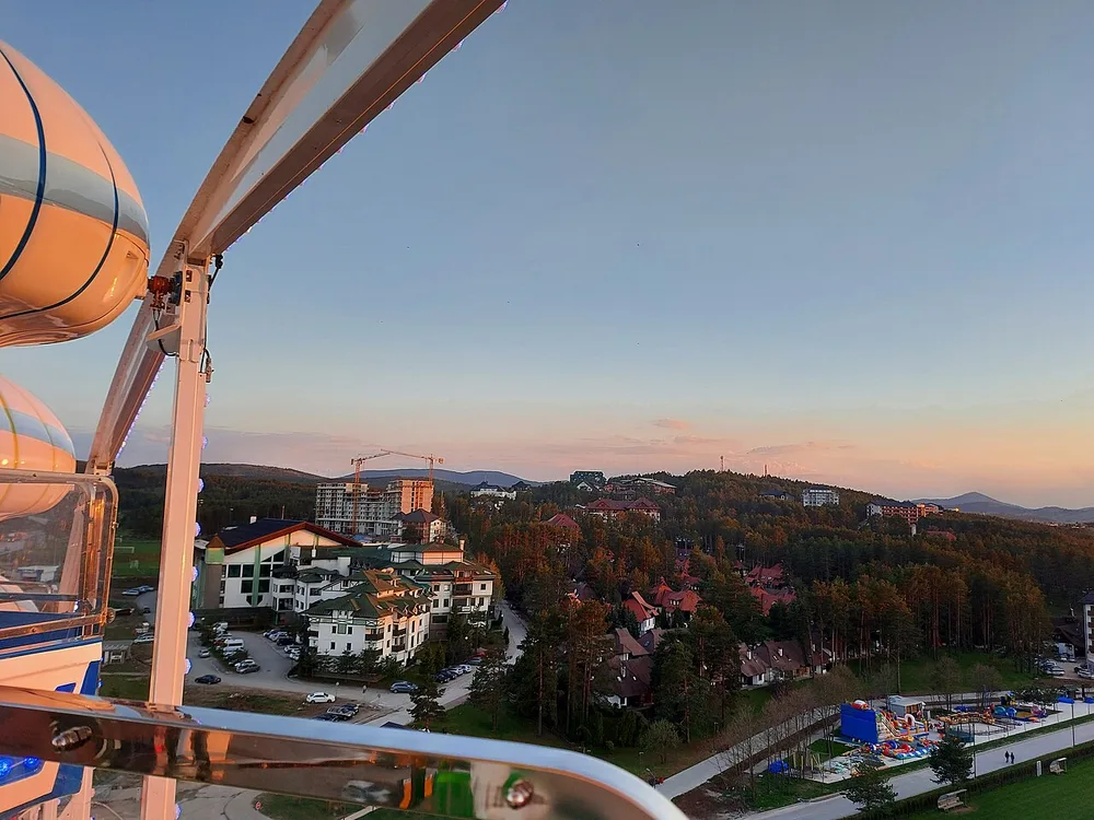 The resort centre of Zlatibor seen from above, with hotels among pine woods and the rounded plateau hills beyond at dusk