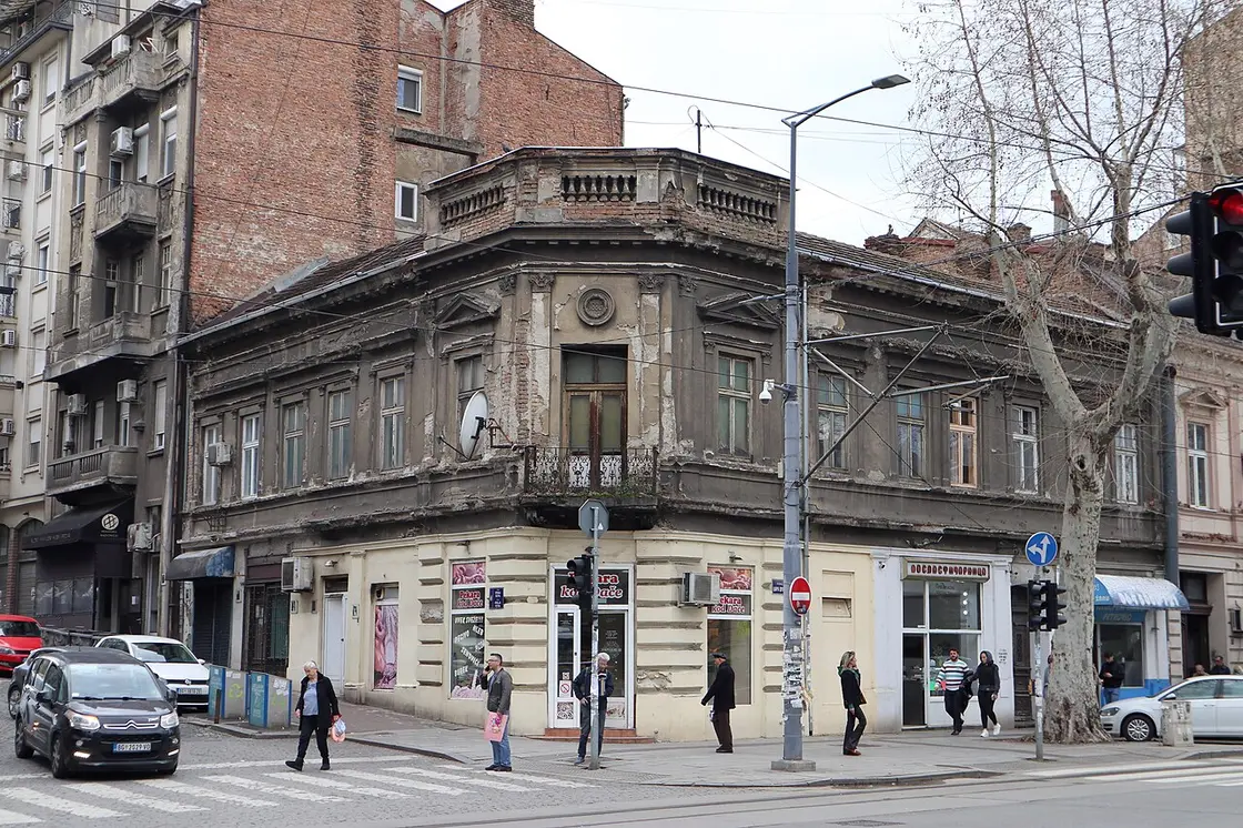 An old faded corner building over small shops on a Dorćol street in Belgrade