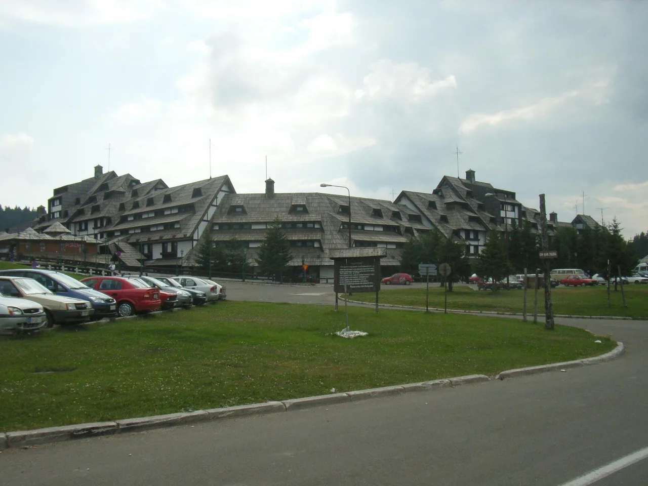 A long shingle-roofed accommodation block in the centre of Kopaonik with cars parked in front