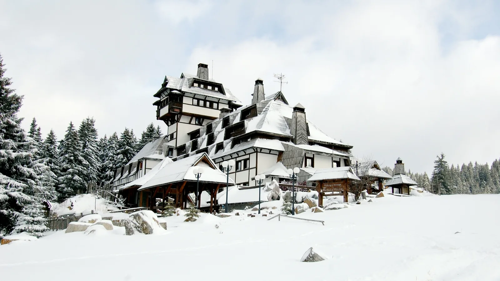 A large timbered ski hotel buried in deep snow on the Kopaonik plateau with spruce forest behind