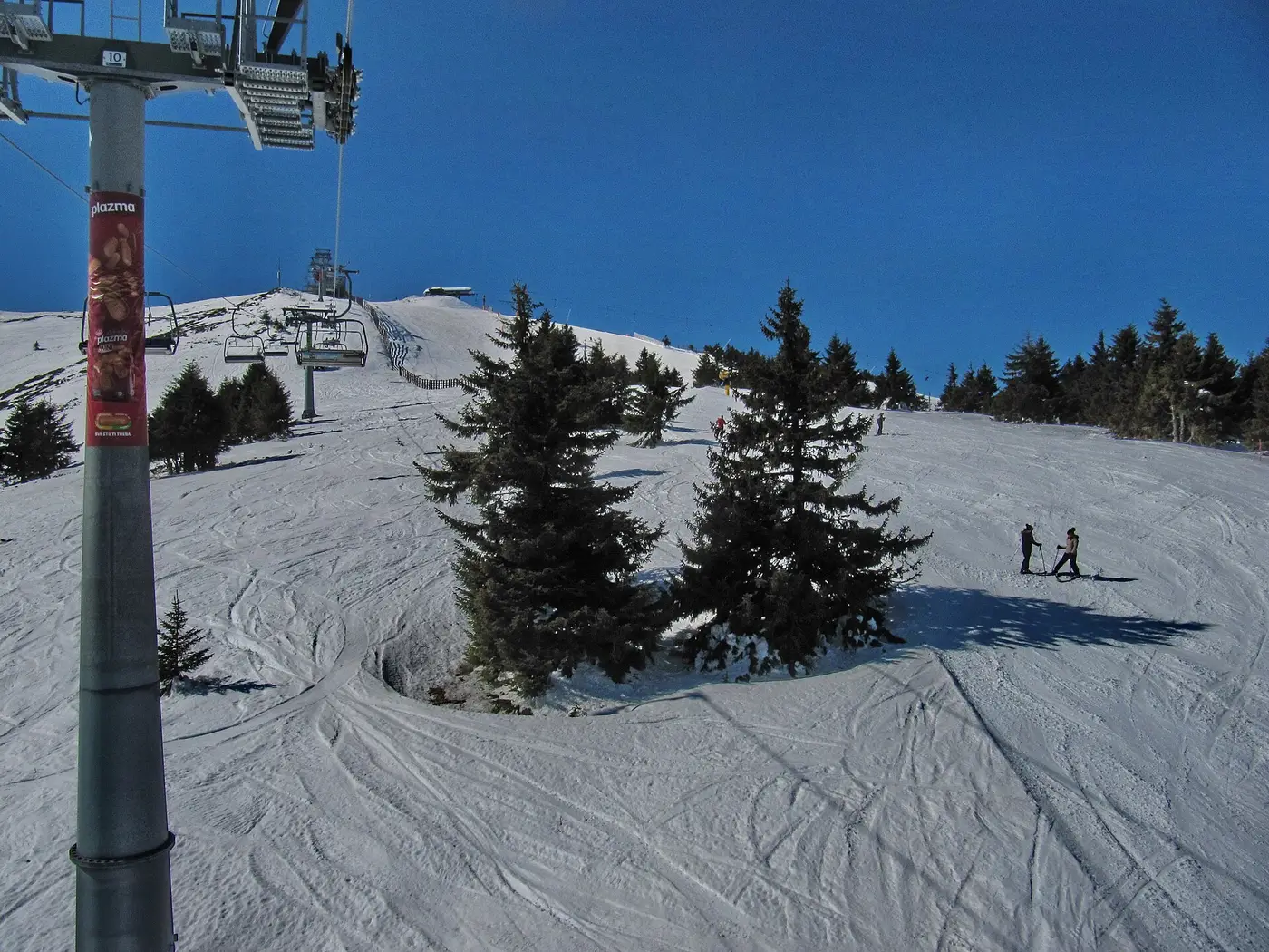 Skiers on a snowy piste under a chairlift at Kopaonik, Serbia